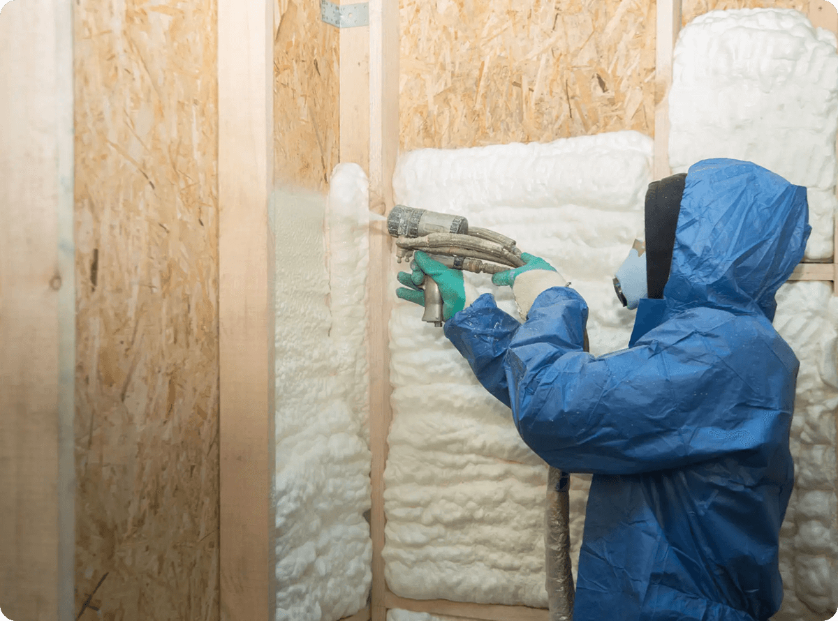 Person in blue suit spraying insulation